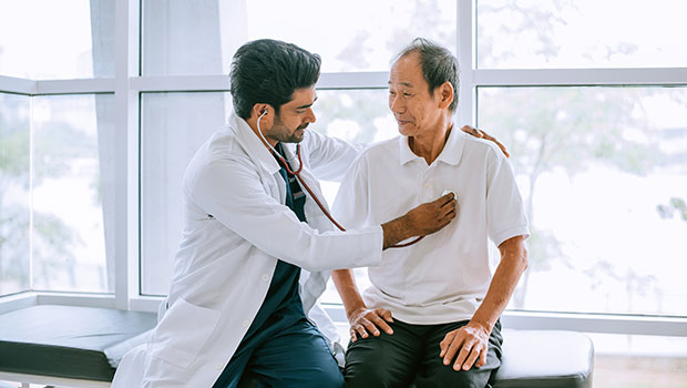 Male doctor checking male patient's heart beat