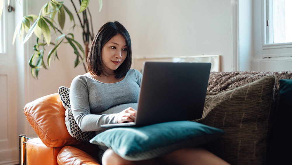 Woman lying on couch on laptop