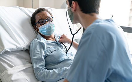 Masked, female African American patient with doctor