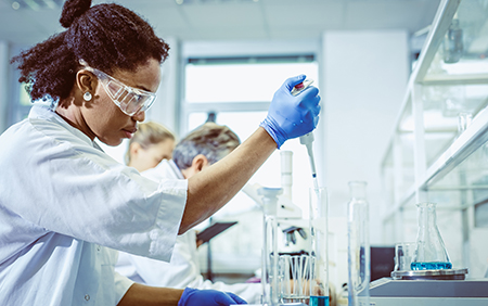 A female scientist is conducting a lab experiment using an automatic pipette. A female scientist is conducting a lab experiment using an automatic pipette.