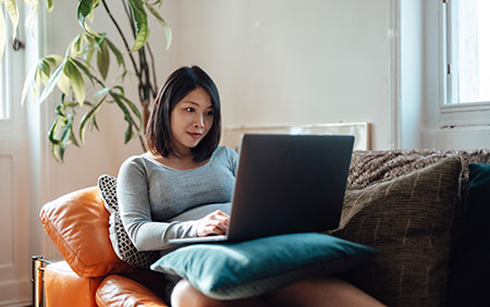 Woman lying on couch on laptop