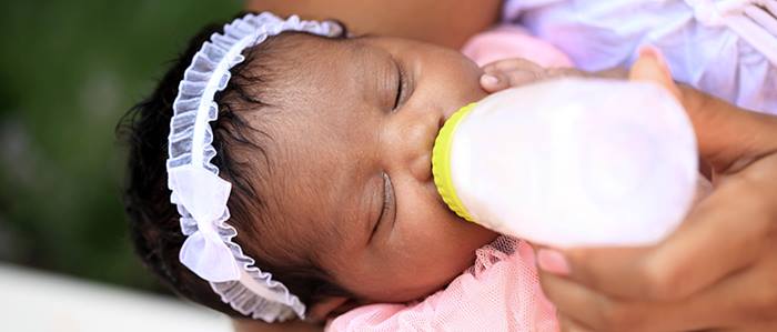 A baby is drinking milk from a bottle