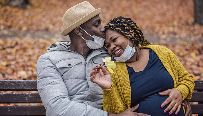 A pregnant couple sits on a bench