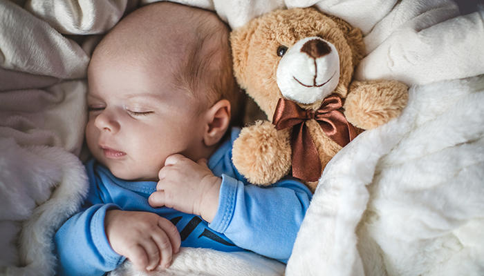 Newborn baby boy sleeping with teddy bear