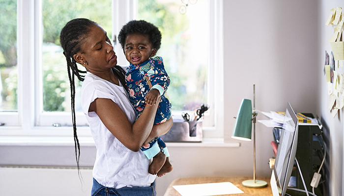 Mother carrying her crying baby son at home.