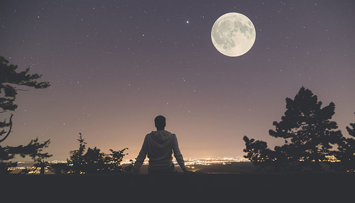 A cancer patient looks up at the stars under a moonlit sky.