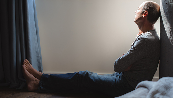 A man seeks mental calmness by sitting on the floor.