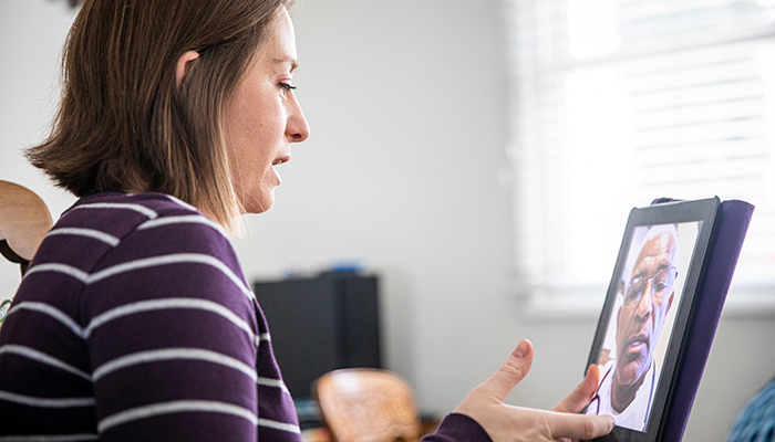 A female patient is attending an online support group on a tablet