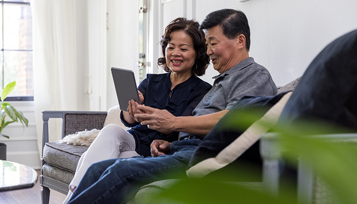 A senior married couple attend an online event on their digital tablet
