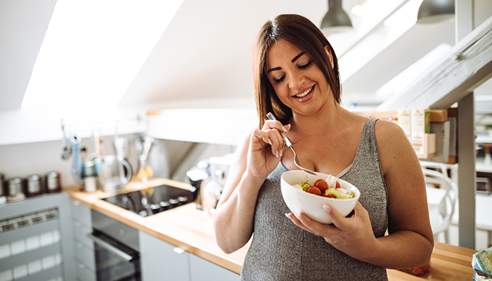 A pregnant woman is eating healthy food at home.