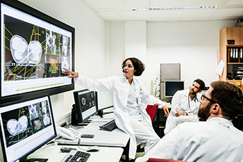 A team of doctors are discussing various cancer clinical trials in a meeting.