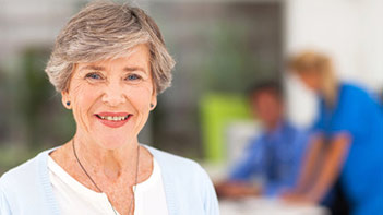 Senior woman smiling with clinicians in background