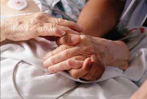 Nurse's hand holding elderly patient's hands