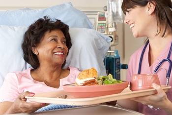 Nurse serving senior female patient a nutritious meal