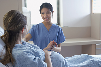 A nurse comforts a pregnant patient during her stay.