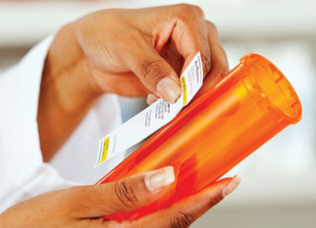 Pharmacist applying label to pill bottle
