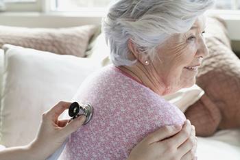 A female patient is getting her lungs checked by a doctor.