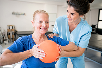 A physical therapist is helping a patient with a rehab exercise.