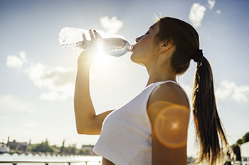 A woman drinking water out of a bottle.