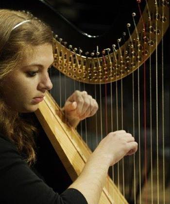 A female musician from BIDMC's Celtic Harp Healing Music Program playing the Celtic Harp.